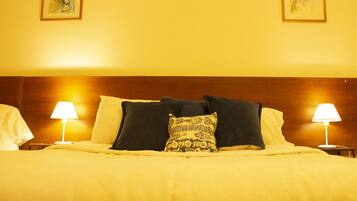 A hotel room with a large bed, two bedside lamps, and two framed artworks on the wall.