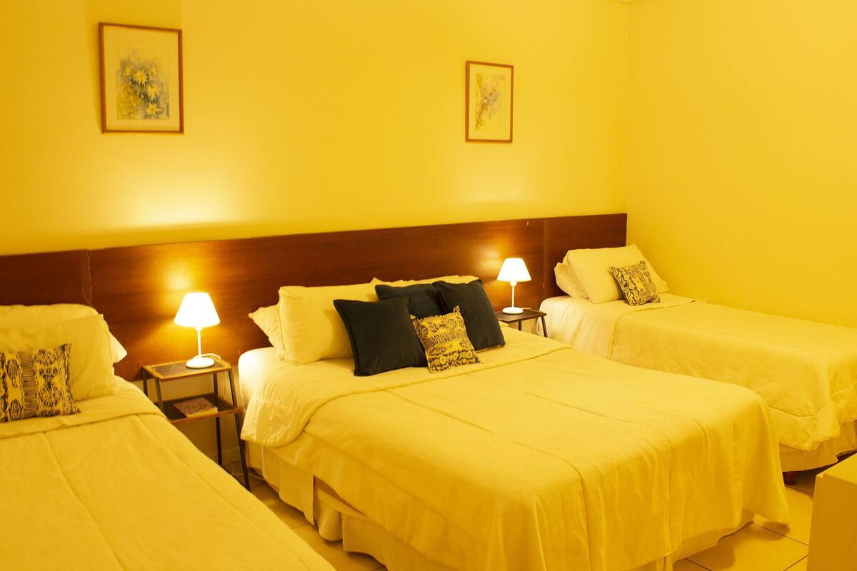 Una habitación de hotel con dos camas, una mesita de noche con lámpara y cabecero.