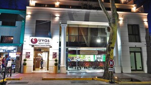 Entrada de un hotel con un letrero que dice "Uvas Apart Hotel" y un restaurante visible en su interior.