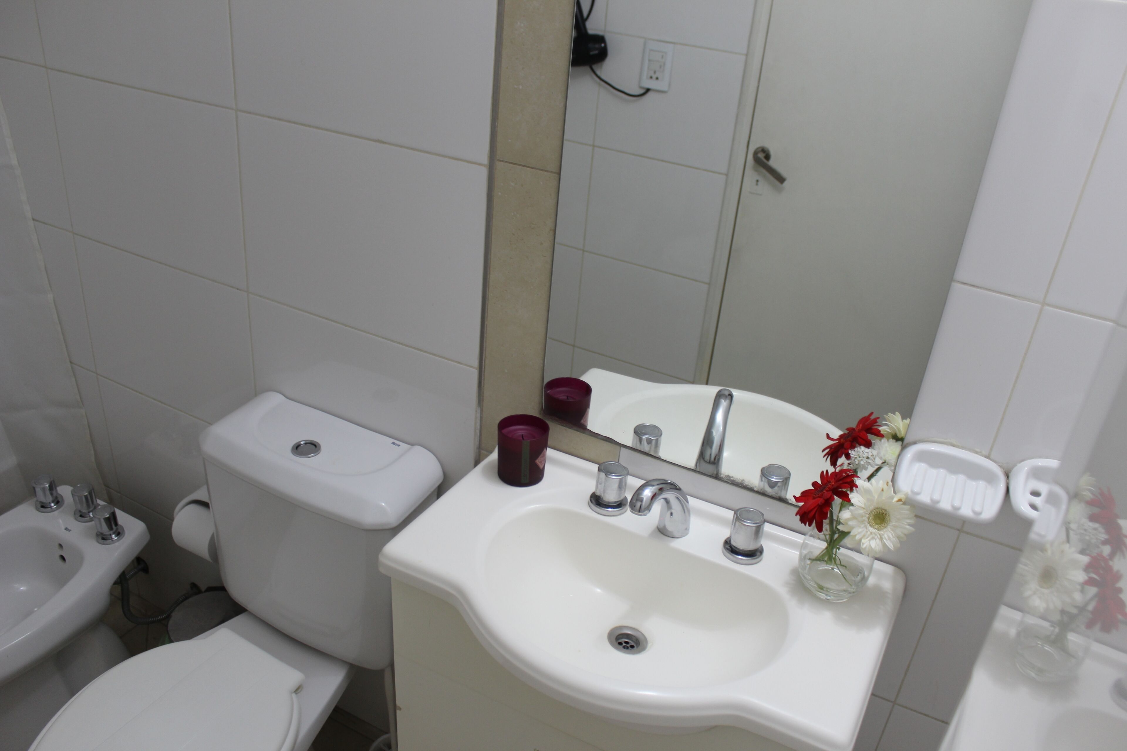 A bathroom with a toilet, bidet, sink, and mirror.