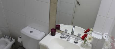 A bathroom with a toilet, bidet, sink, and mirror.