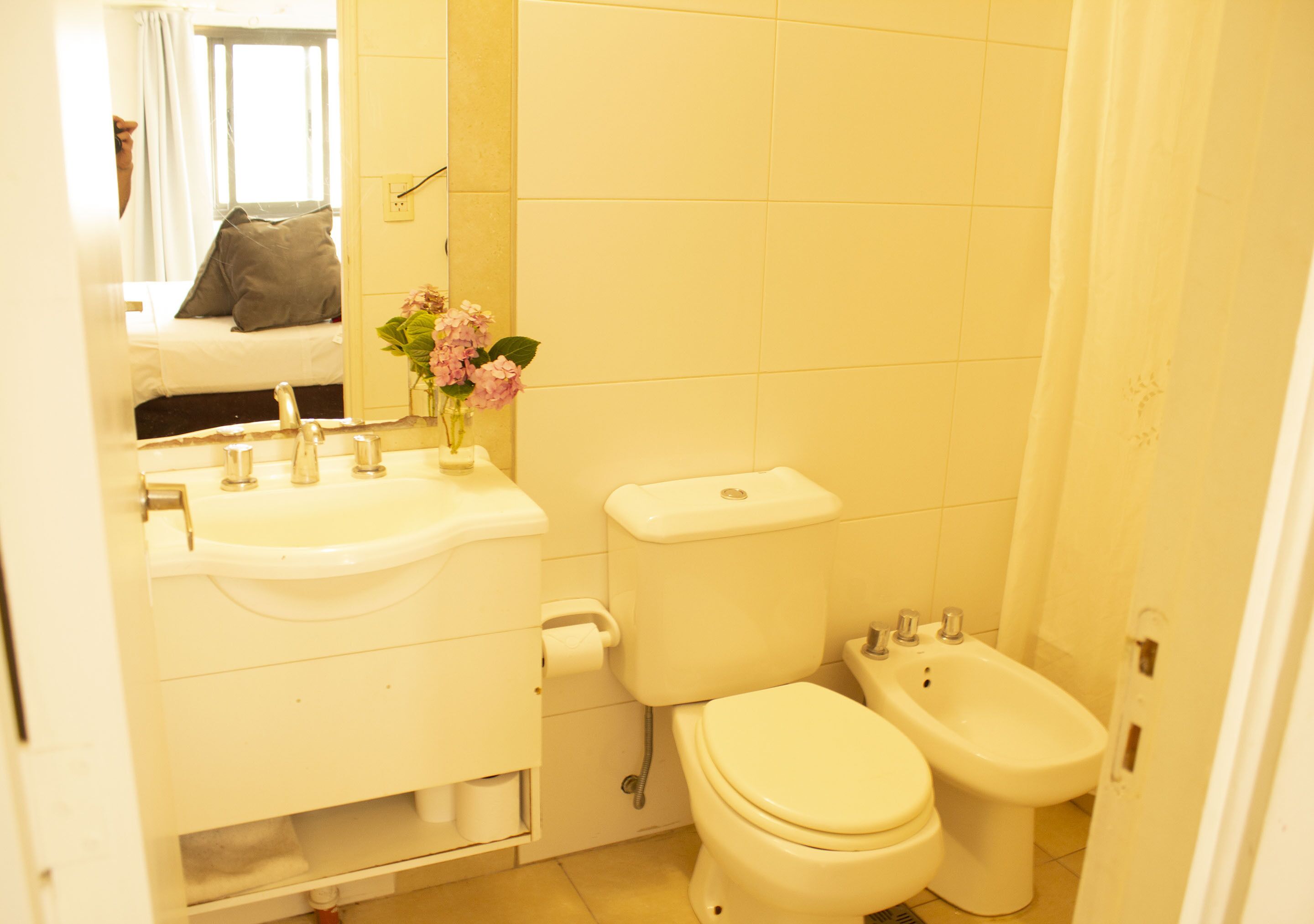 Een kleine badkamer met toilet, wastafel, spiegel en bidet.