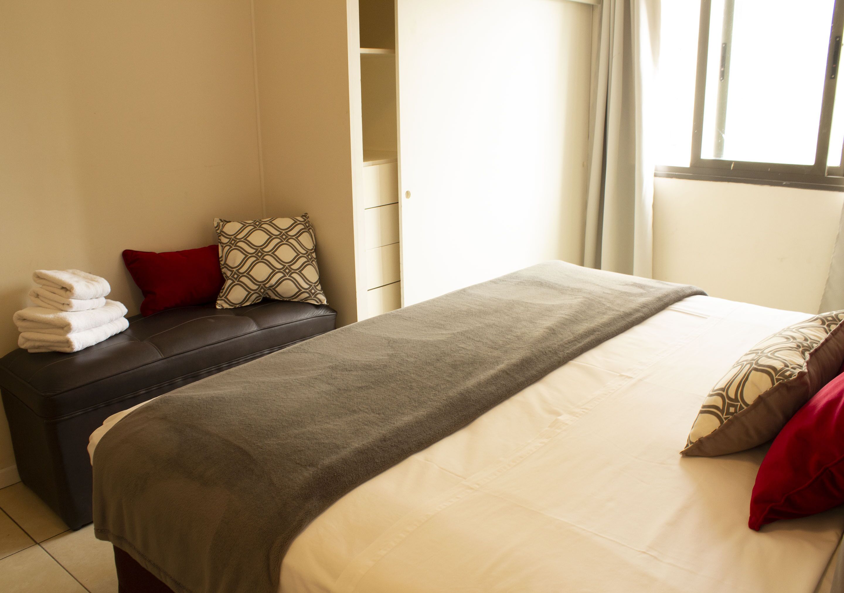 A bedroom with a bed, a bench, and a wardrobe.
