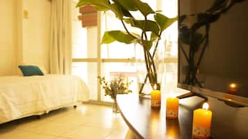 Una habitación de hotel con una cama, una planta en maceta y velas sobre una mesa.