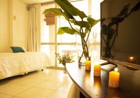Una habitación de hotel con una cama, una planta en maceta y velas sobre una mesa.