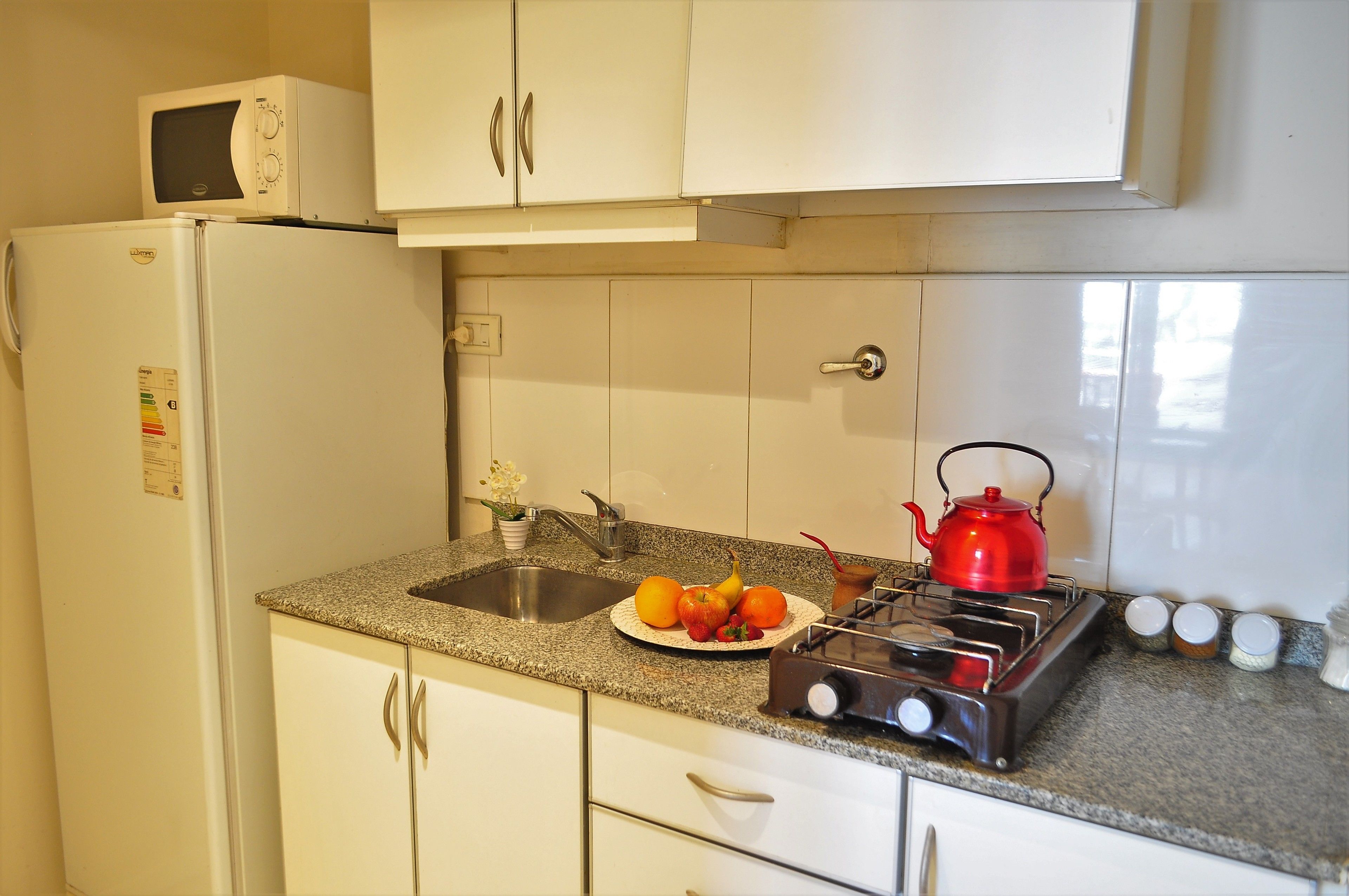 A kitchen with a refrigerator, microwave, sink, stove, and cabinets.