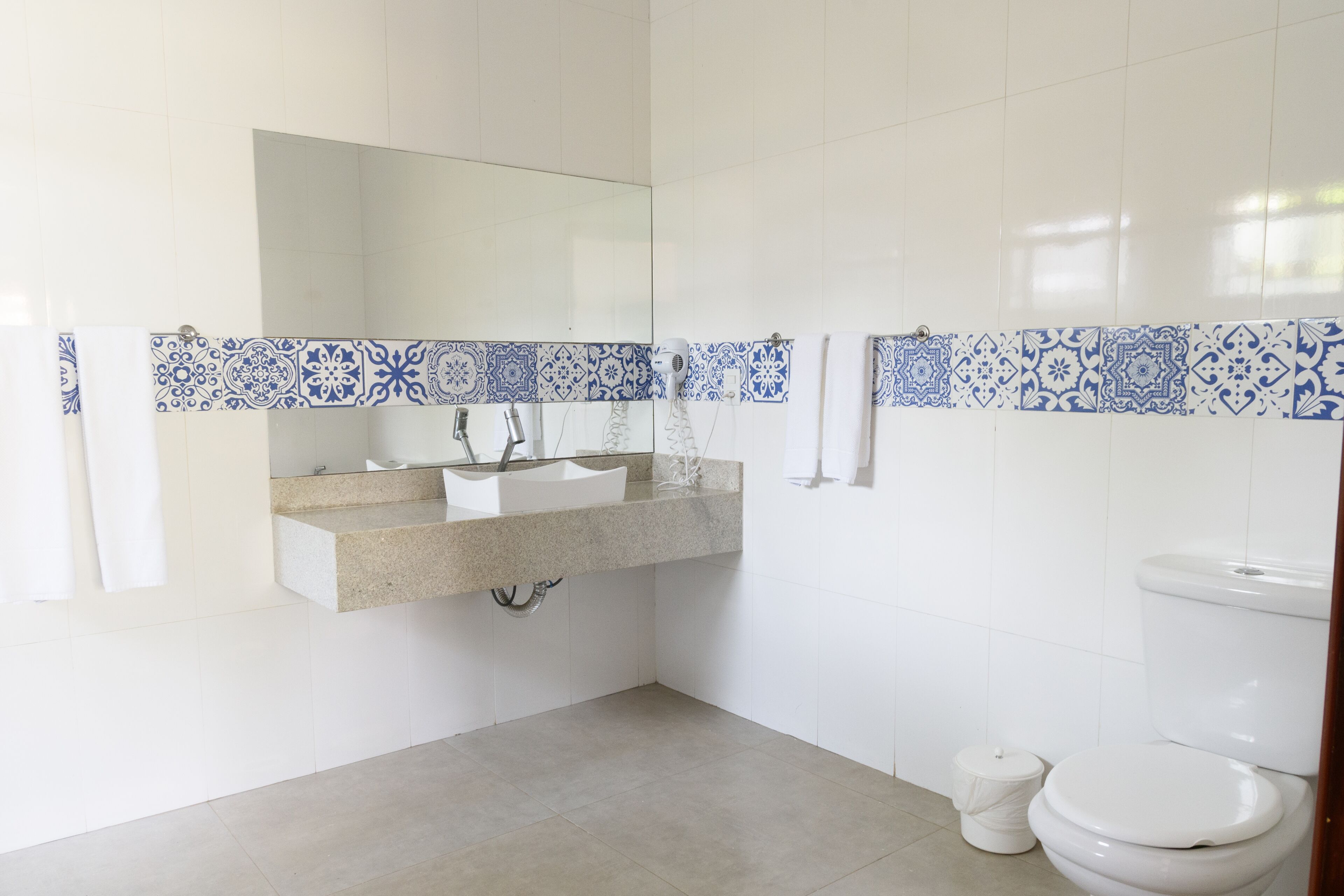 A bathroom with a white sink, mirror, and toilet.