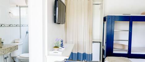 Habitación pequeña con inodoro, lavabo y una cama doble.