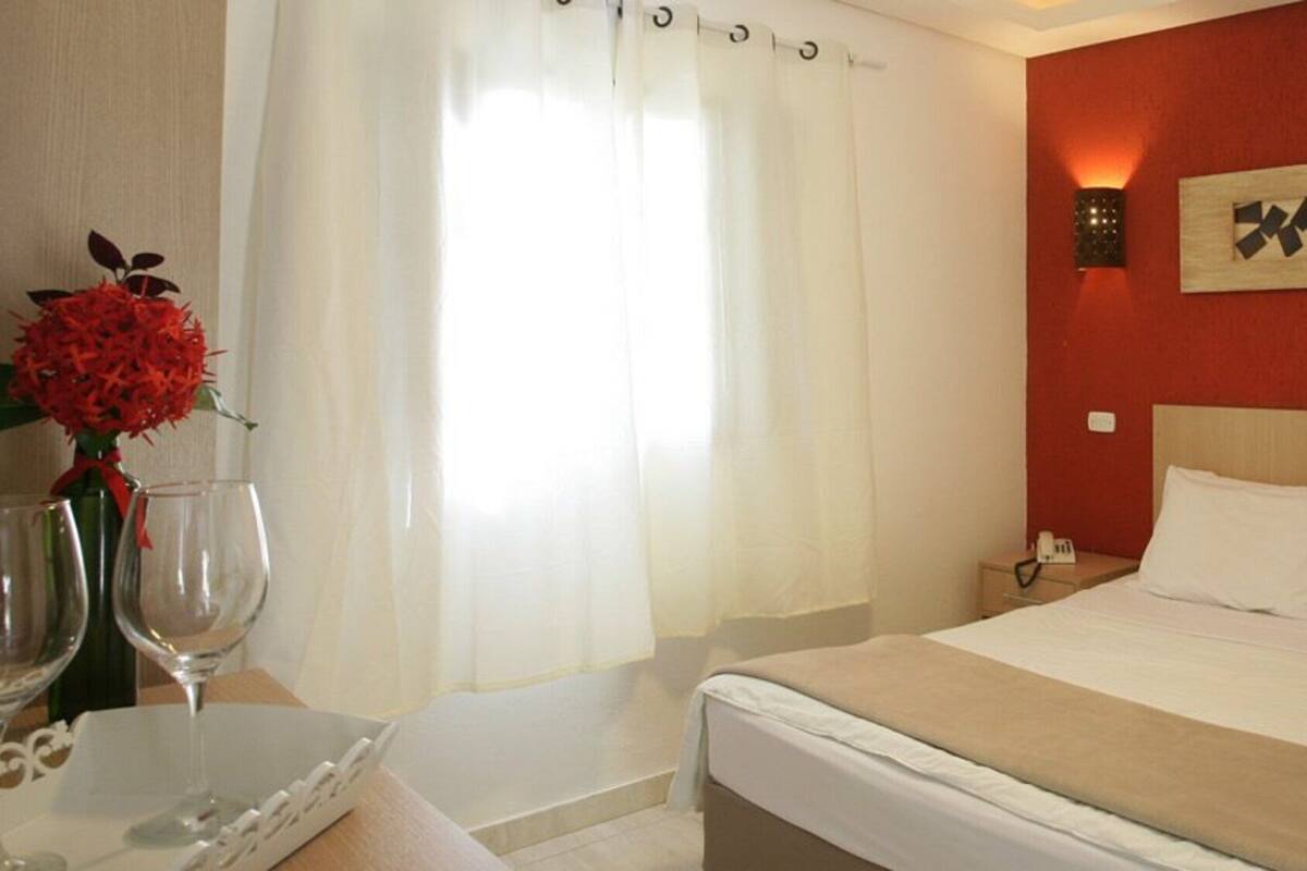 Ein Hotelzimmer mit Bett, Nachttisch und einem an der Wand befestigten Kunstwerk.