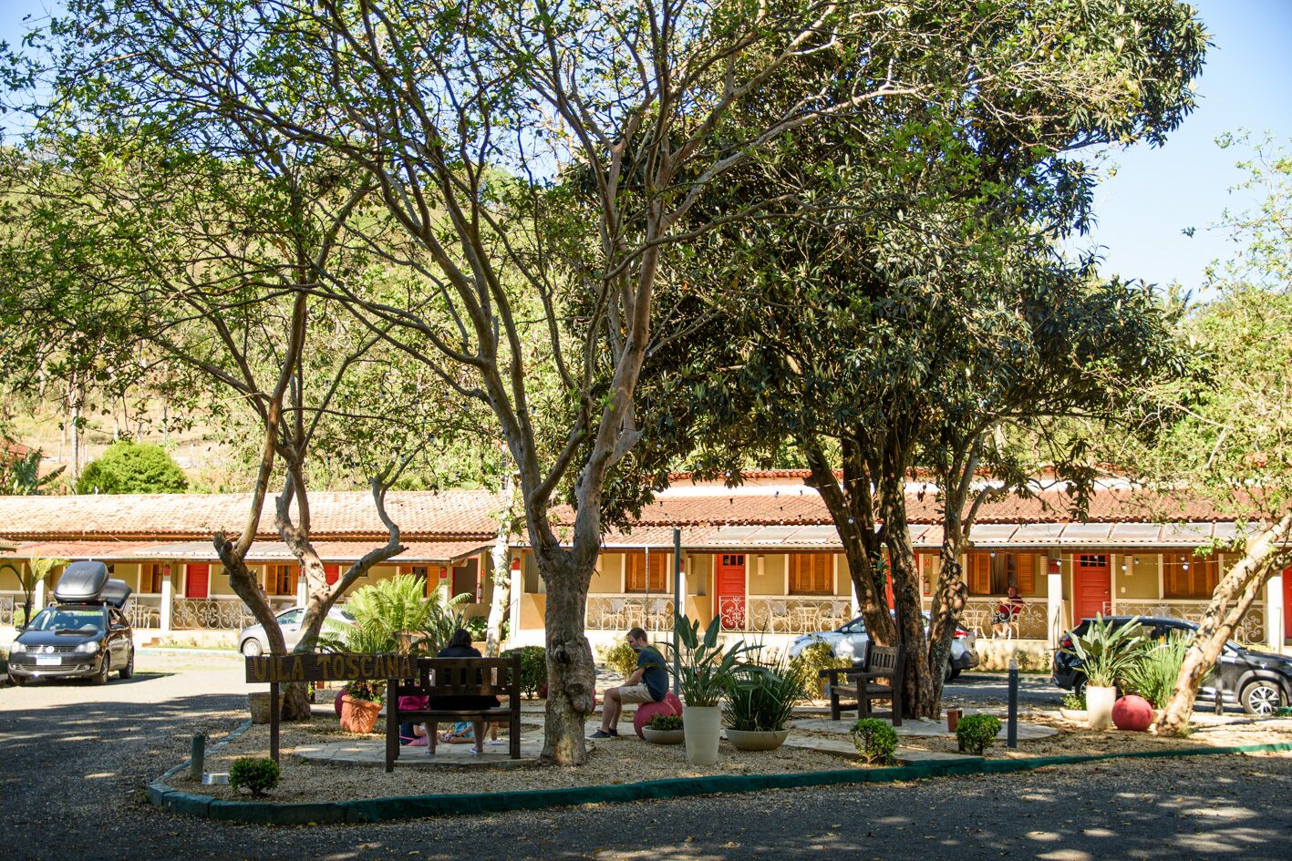 A hotel with outdoor seating, potted plants, and a clear view of the surrounding area.
