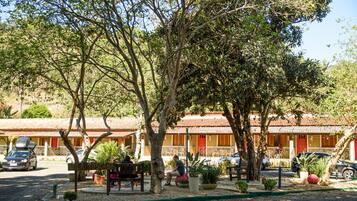 A hotel with outdoor seating, potted plants, and a clear view of the surrounding area.