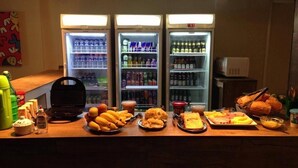 A buffet counter with various food items and beverages. - Koze Hostel (Florianópolis)