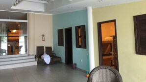 A spacious indoor area with a high ceiling, a staircase leading to an upper level, and a seating area with chairs. - Koze Hostel (Florianópolis)