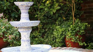 Una fuente de cerámica azul y blanca de varios niveles en un jardín.