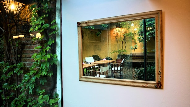 Una habitación con un espejo grande que refleja un comedor, una pared de ladrillo y luces colgantes.
