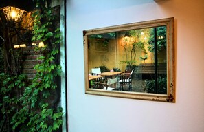 A room with a large mirror reflecting a dining area, a brick wall, and hanging lights. - La Manuel Lobo Posada (Colonia del Sacramento)