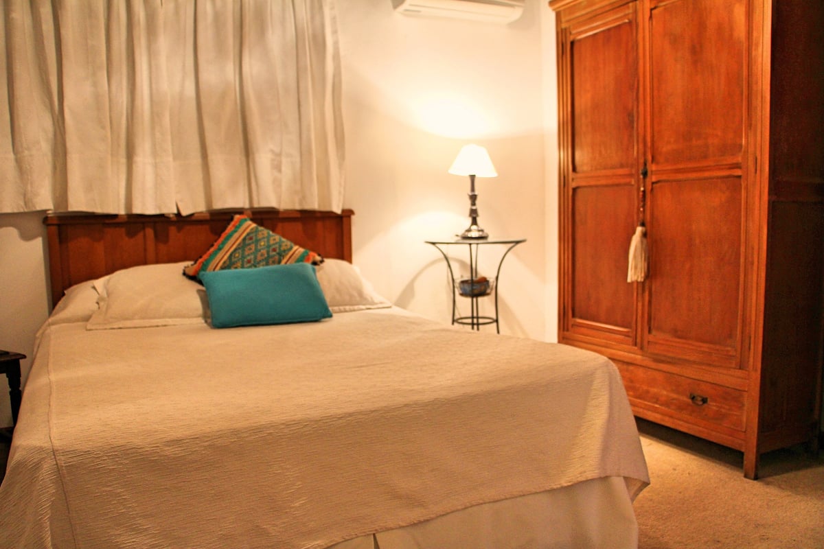 A bedroom with a bed, a nightstand, a lamp, and a wardrobe.
