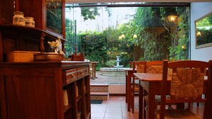 Comedor de madera con vista a un jardín y una fuente.