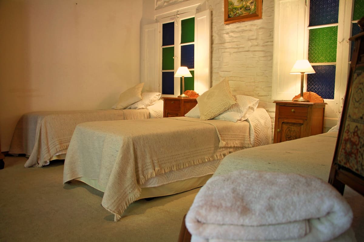 A hotel room with two beds, each with a bedside table and lamp.
