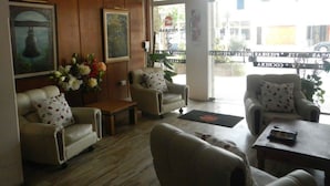 A hotel lobby with leather sofas, a wooden coffee table, and a large window with a view of the street. - Hotel Piedras (San Clemente)