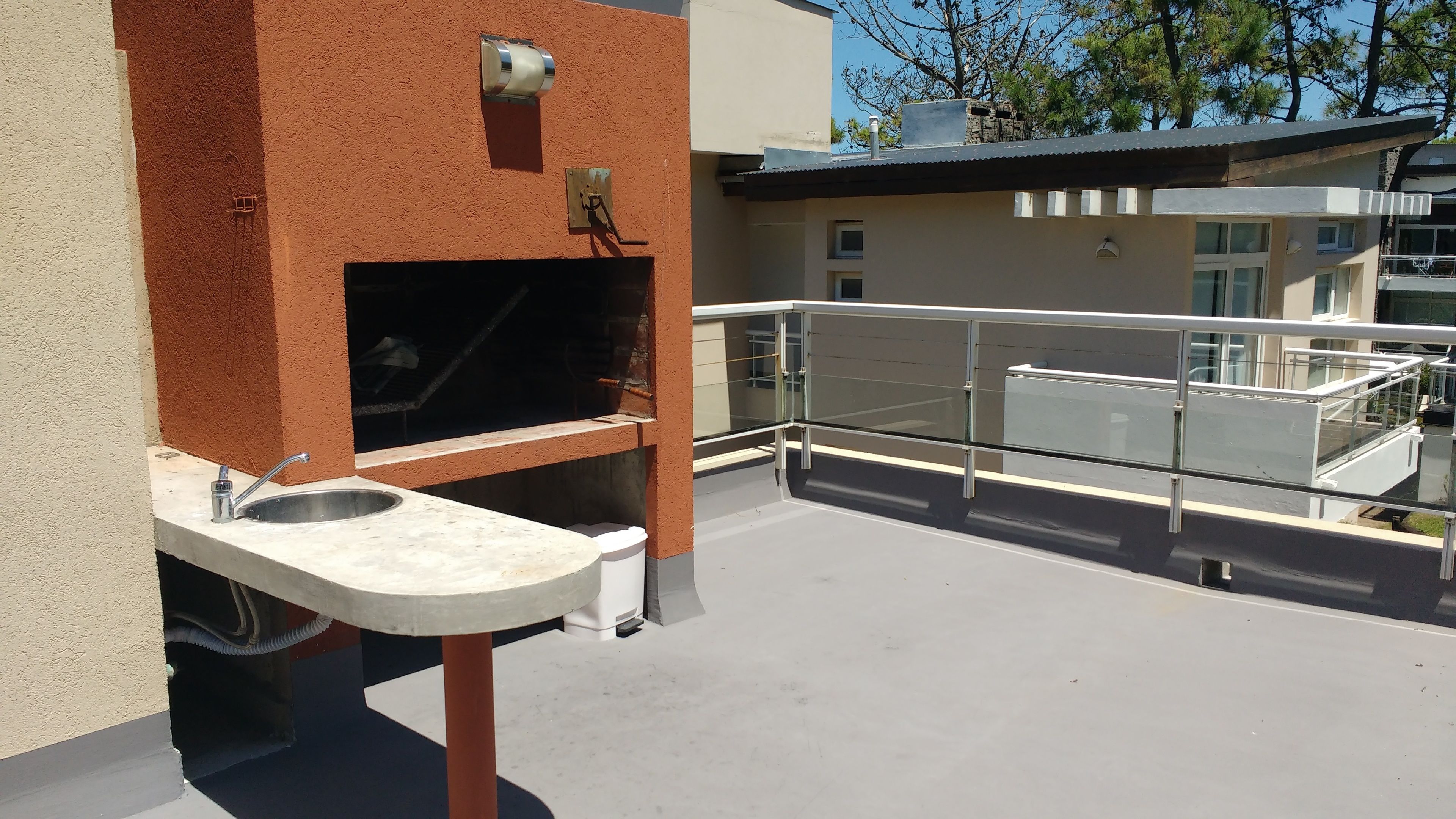 A rooftop terrace with a barbecue grill, a sink, and a railing.