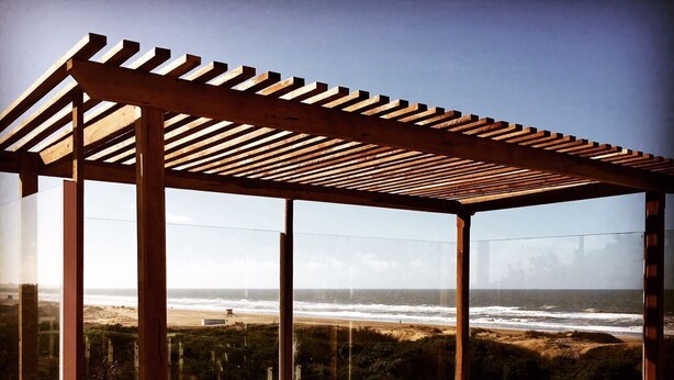 A wooden deck with a hot tub overlooking a beach. - Jaina Resort & Spa (Mar de Las Pampas)