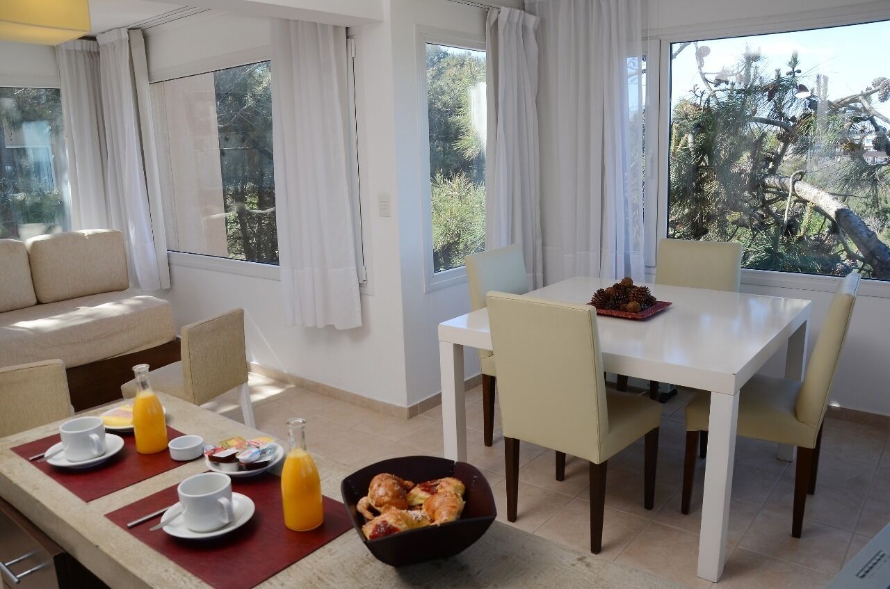 Un coin repas avec une table mise pour le petit-déjeuner, comprenant des assiettes, des tasses et un bol de viennoiseries.