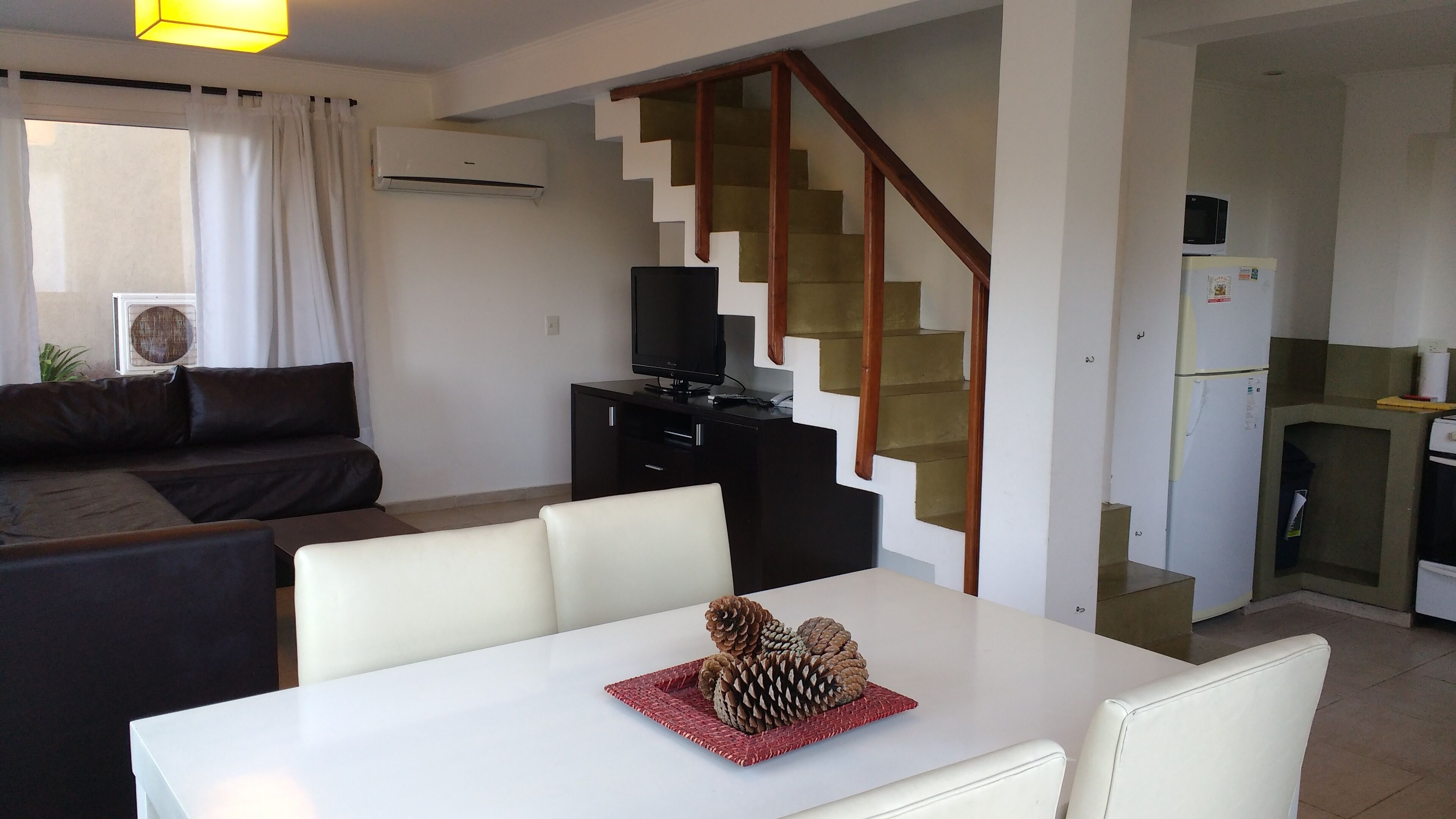 A modern living space with a staircase, a dining area, a kitchen, and a sofa.