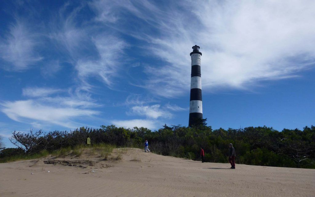 A lighthouse on a sandy beach with a clear sky.