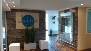 A modern interior with a stone wall, a sign reading "Jina resort & spa", and a wooden floor. - Jaina Resort & Spa (Mar de Las Pampas)