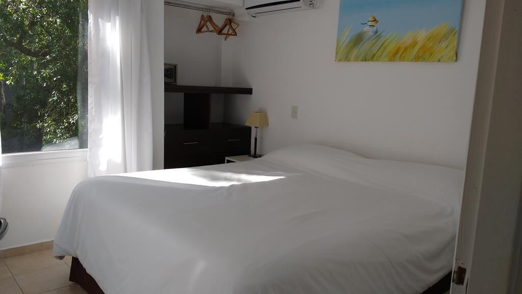 A bedroom with a bed, a nightstand, a lamp, and a painting on the wall.