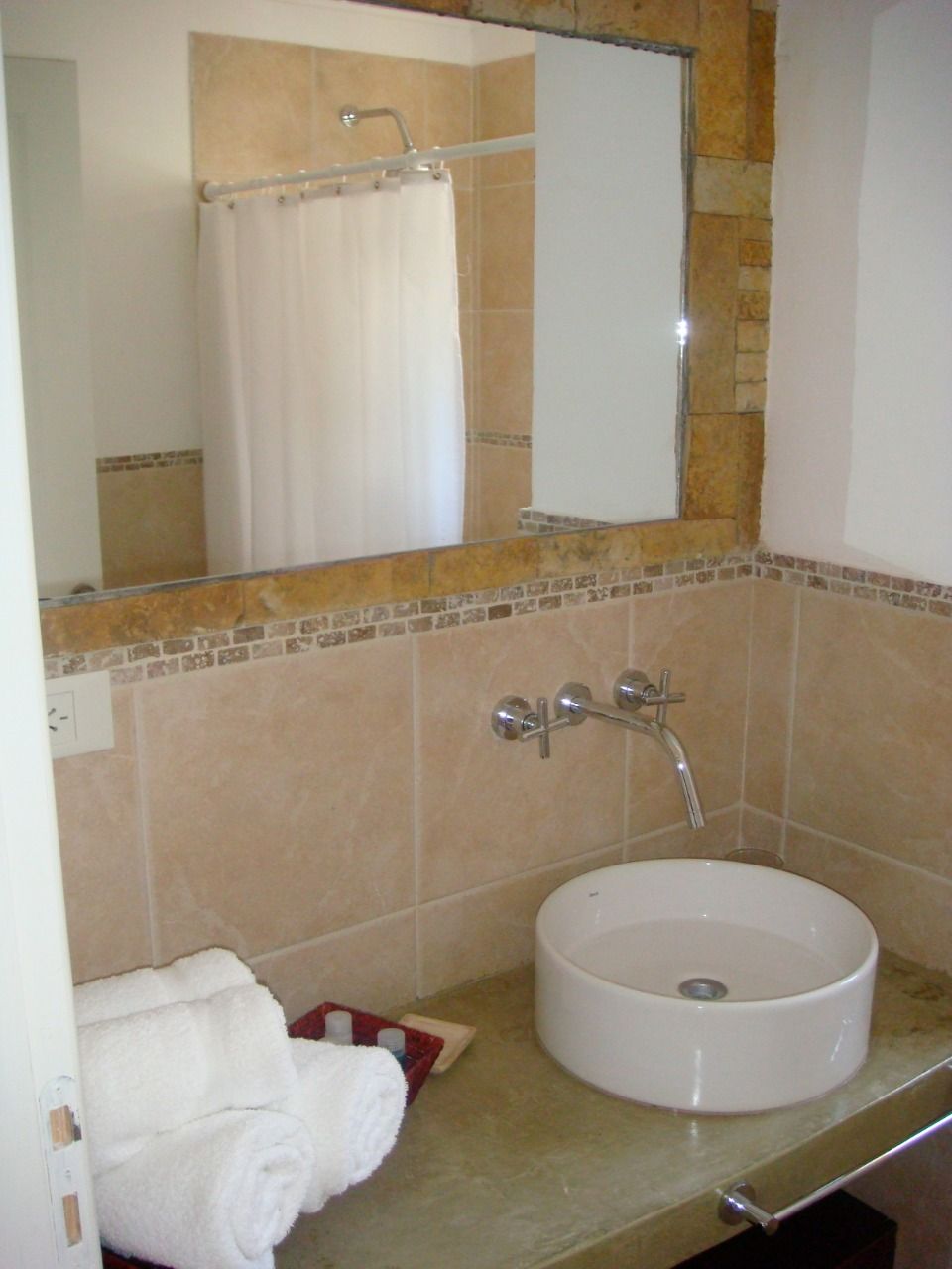 Une salle de bain avec un lavabo blanc, un miroir et un rideau de douche.
