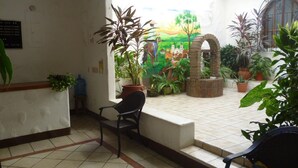 Una zona de recepción con suelo de baldosas, mostrador de recepción, una silla y plantas en macetas.
