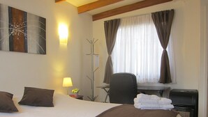 Ein Hotelzimmer mit einem großen Bett, einem Schreibtisch, einem Stuhl und einem Fenster mit Vorhängen.