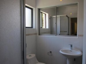 A bathroom with a toilet, a sink, and a mirror. - Hotel 7 Norte (Vina del Mar)