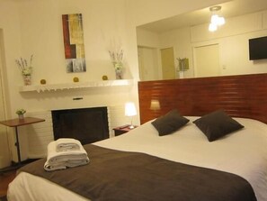A hotel room with a large bed, a fireplace, a flat-screen TV, and a mirror on the wall. - Hotel 7 Norte (Vina del Mar)
