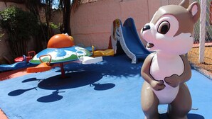 A playground with a slide, climbing structures, and a large animal statue. - Bica Pau Hotel Thermas (Caldas Novas)