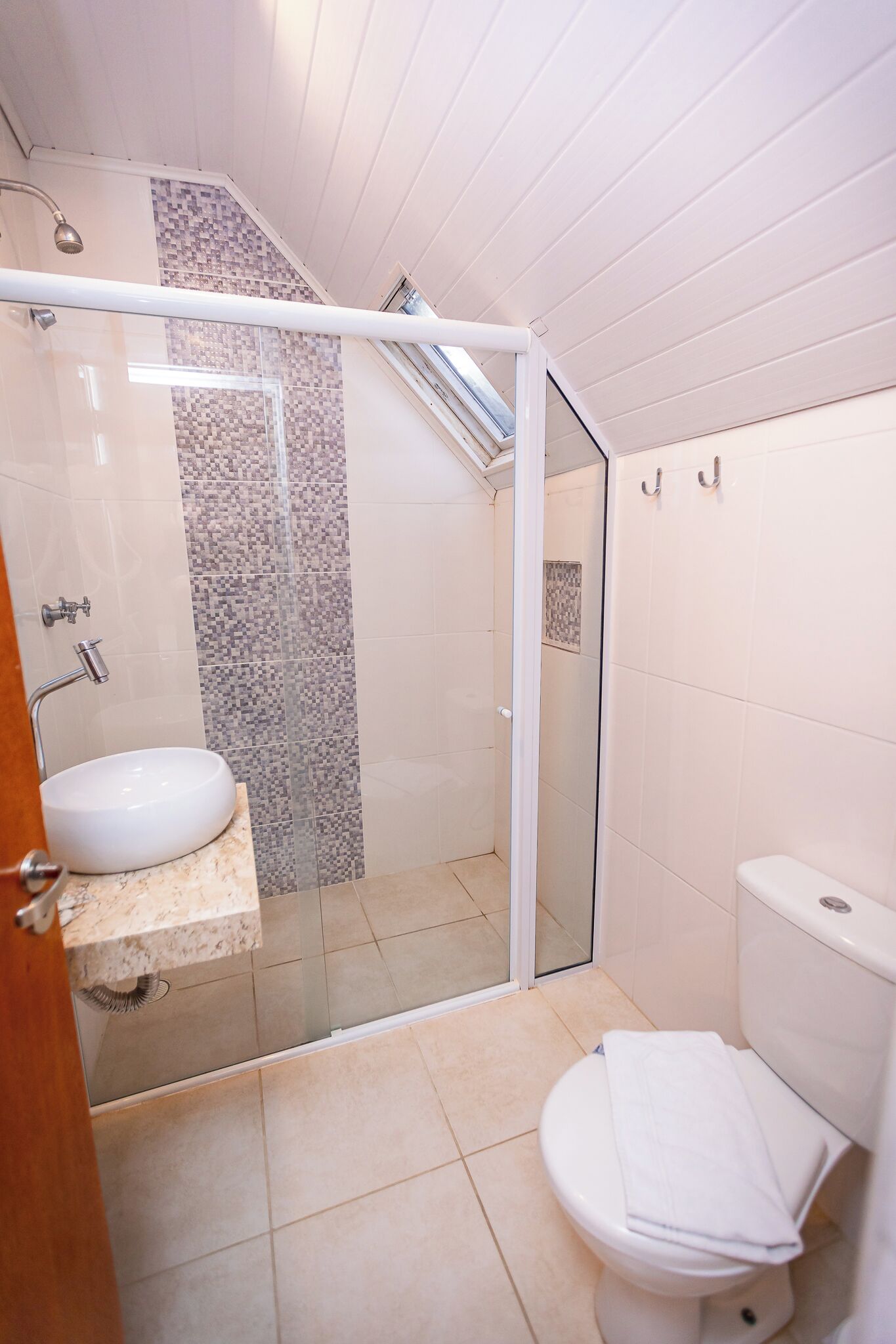 A bathroom with a glass-enclosed shower, a sink, and a toilet.