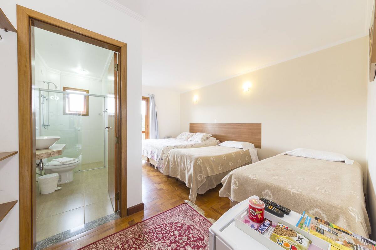 Habitació d'hotel amb dos llits, un bany i una petita taula amb aperitius i un comandament a distància.