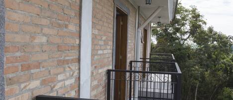 A brick building with a balcony featuring a black metal railing and a wooden door.