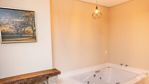 A modern bathroom with a large bathtub, a stone fireplace, and a hanging light fixture. - Villa Hegus (Campos do Jordão)