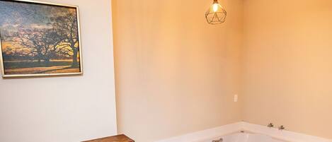 Une salle de bain moderne avec une grande baignoire, une cheminée en pierre et un luminaire suspendu.