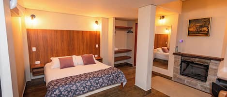 Hotellihuone, jossa on sänky, takka ja puinen pääty.