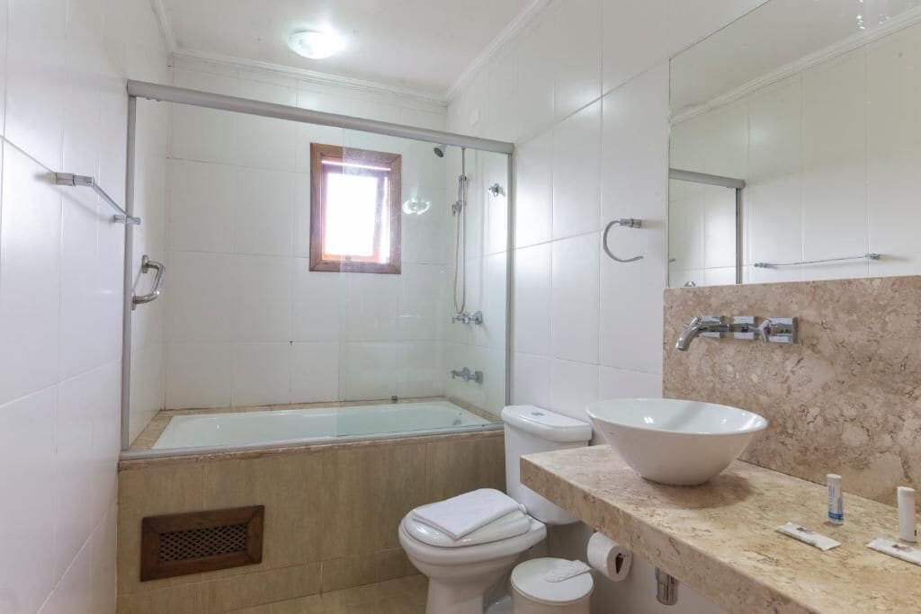 Een badkamer met een bad, toilet, wastafel en een grote spiegel.
