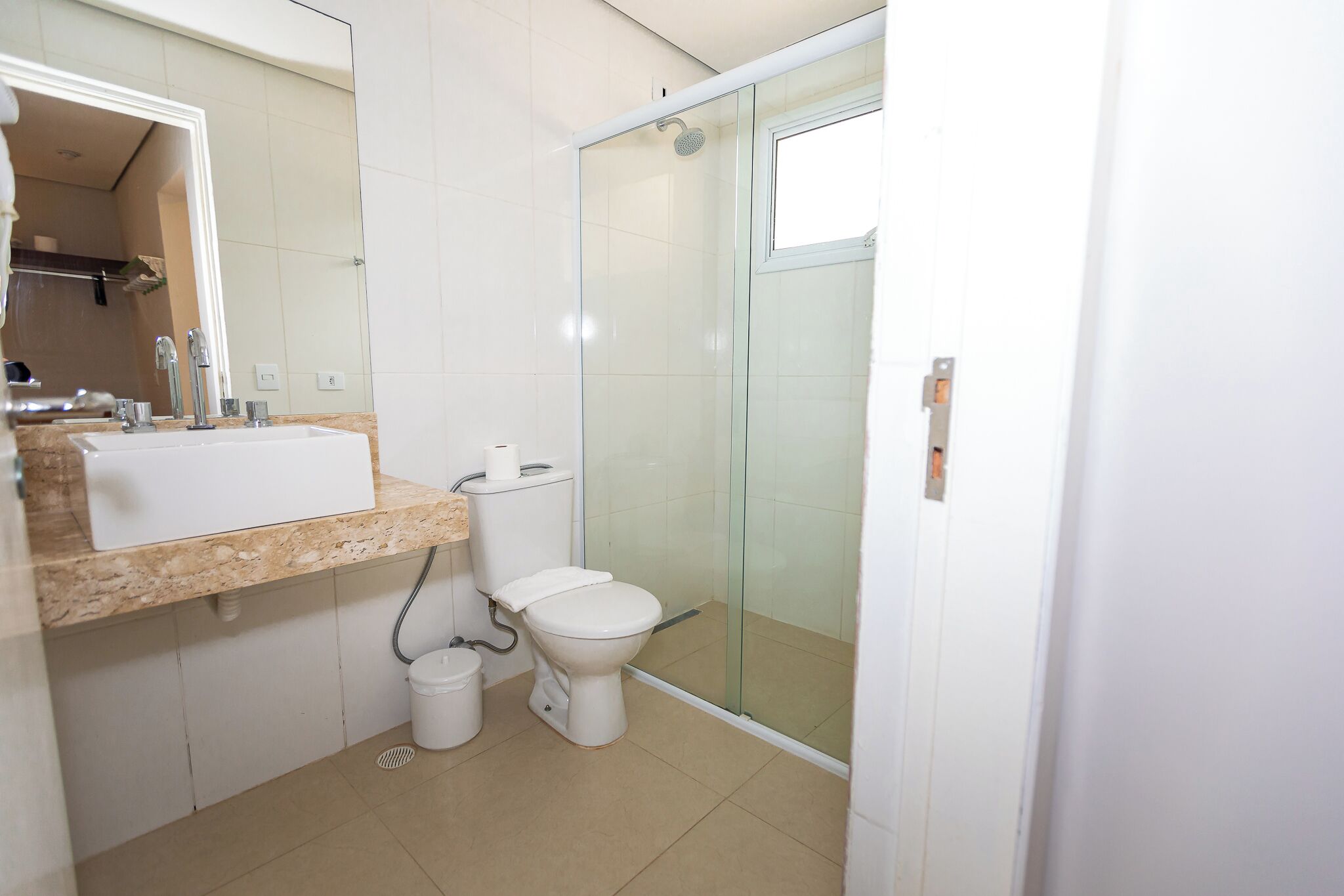 Un bany amb rentapel, vàter i cabina de dutxa de vidre.