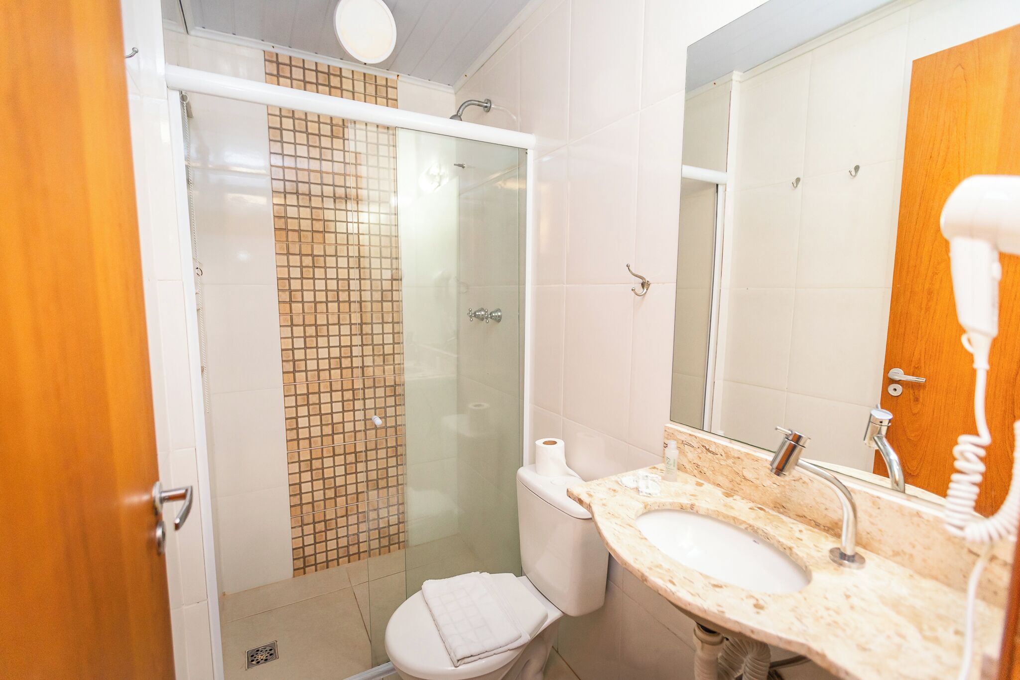 A bathroom with a glass shower enclosure, a toilet, a sink with a mirror, and a towel rack.