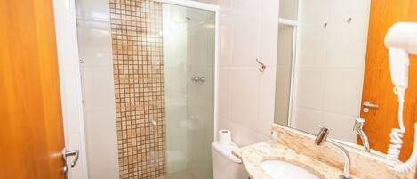 A bathroom with a glass shower enclosure, a toilet, a sink with a mirror, and a towel rack.