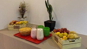 Una mesa de buffet con diversas frutas, una planta en maceta y un jarrón de flores secas.