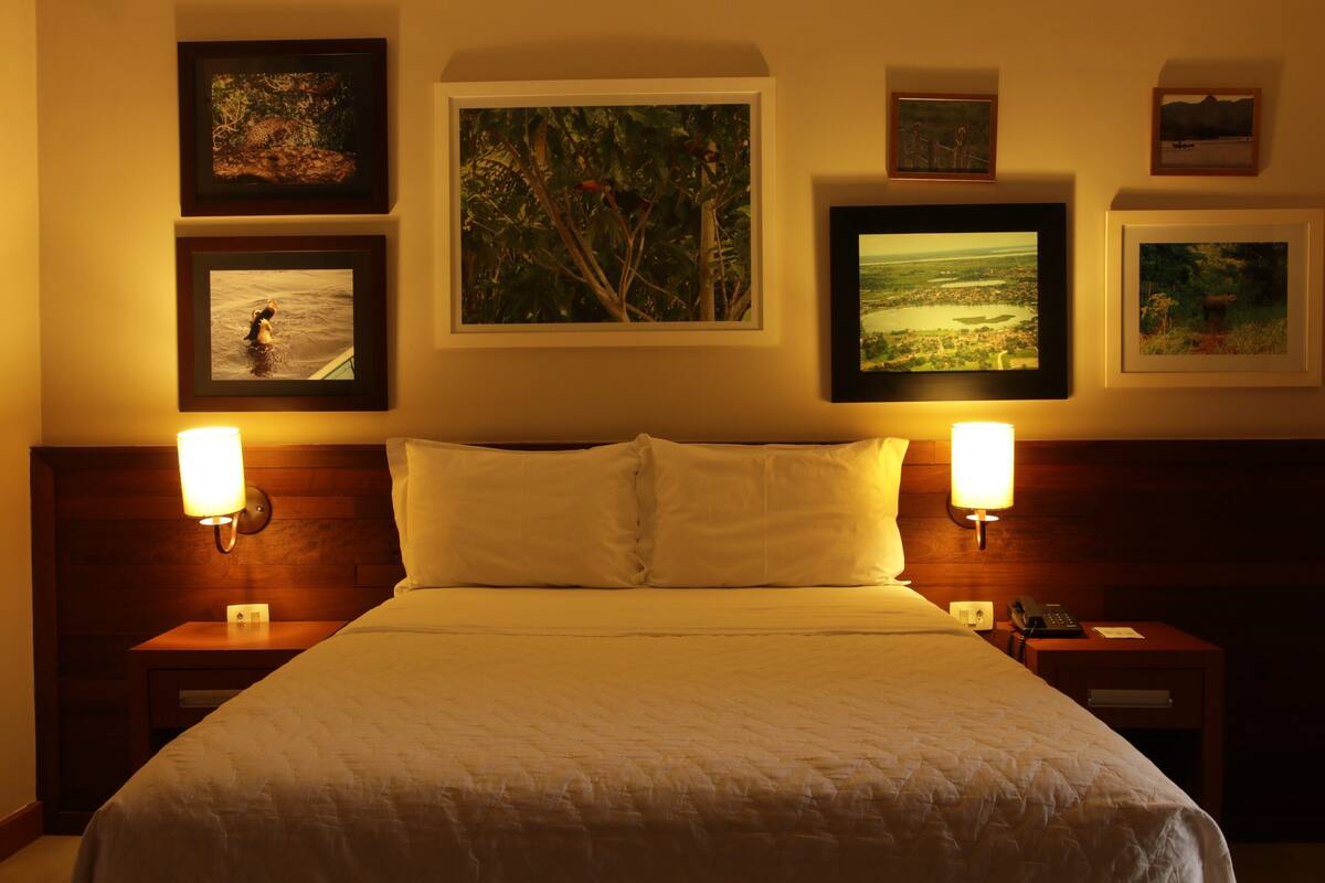 A hotel room with a large bed, two bedside tables, and four framed pictures on the wall.