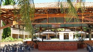 An outdoor patio area with a covered seating area, a pool, and a sign indicating a restaurant. - Hotel OT (Tres Lagoas)